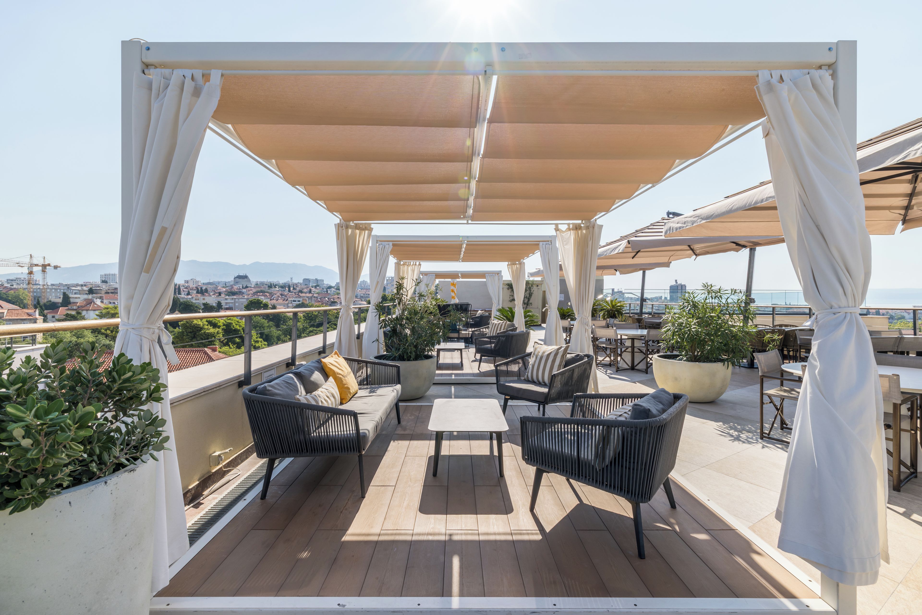 Una terraza al aire libre con asientos, vista a la ciudad y una estructura de pérgola.