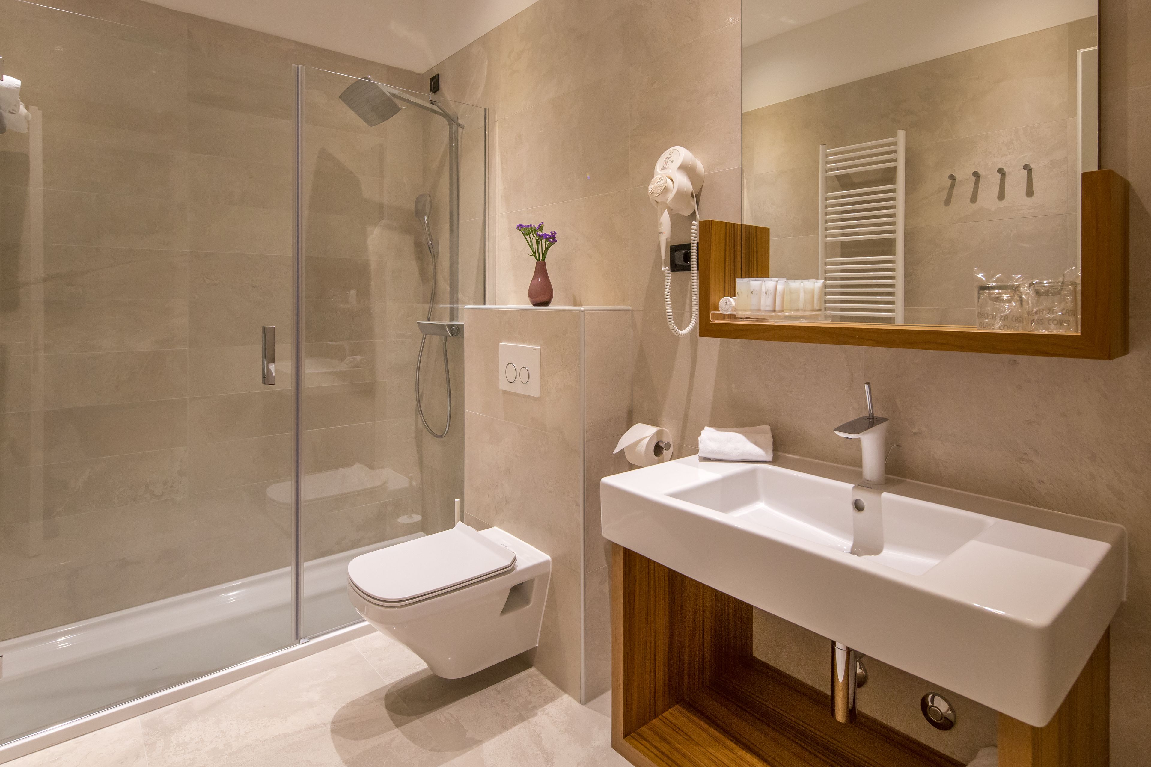 Un bagno moderno con cabina doccia in vetro, un water bianco, un mobile lavabo e uno specchio.