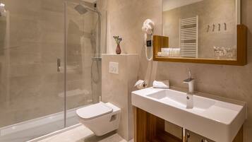 Un baño moderno con cabina de ducha de vidrio, inodoro blanco, tocador con lavabo y espejo.