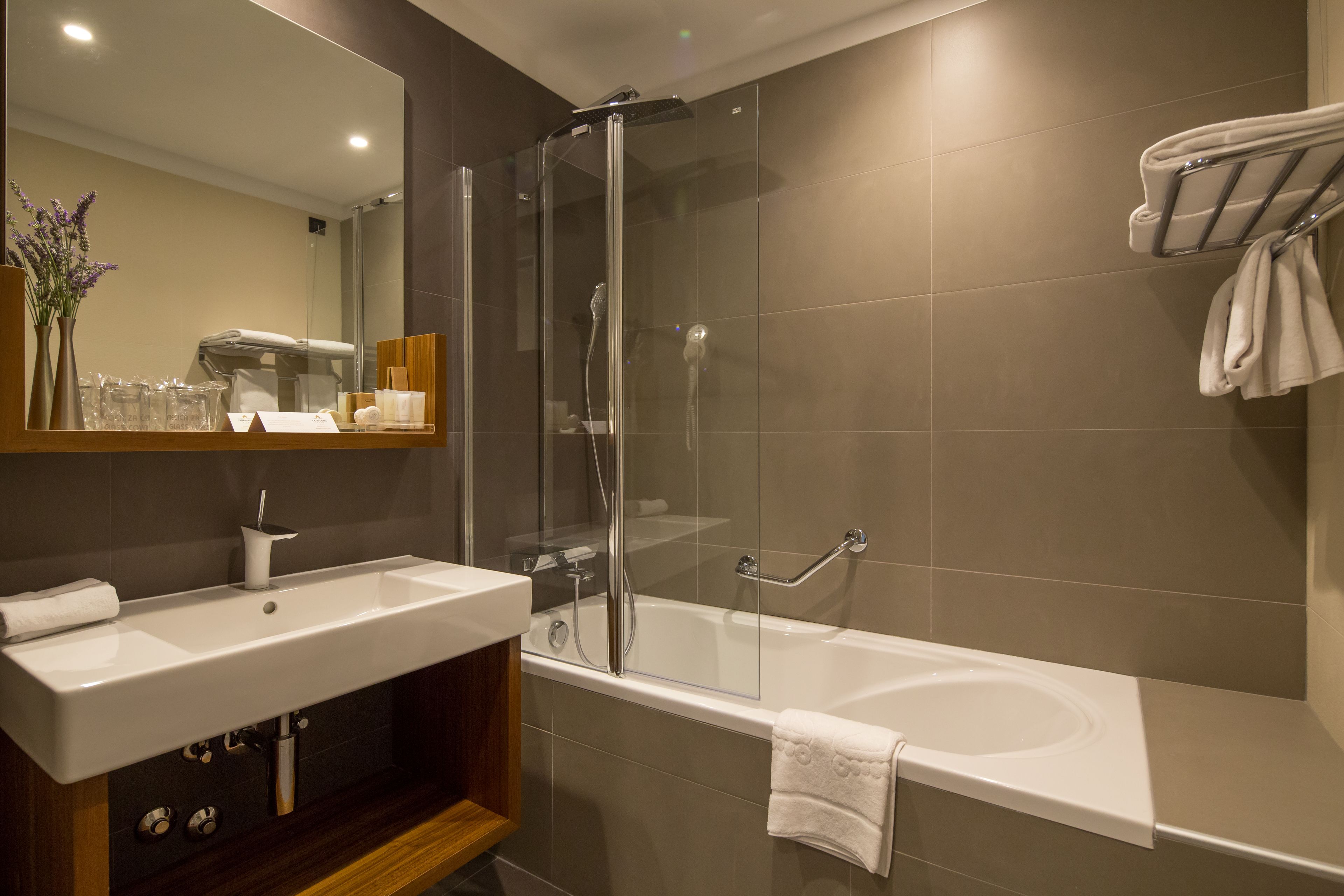 A modern bathroom with a glass-enclosed shower, a white bathtub, and a vanity with a mirror.