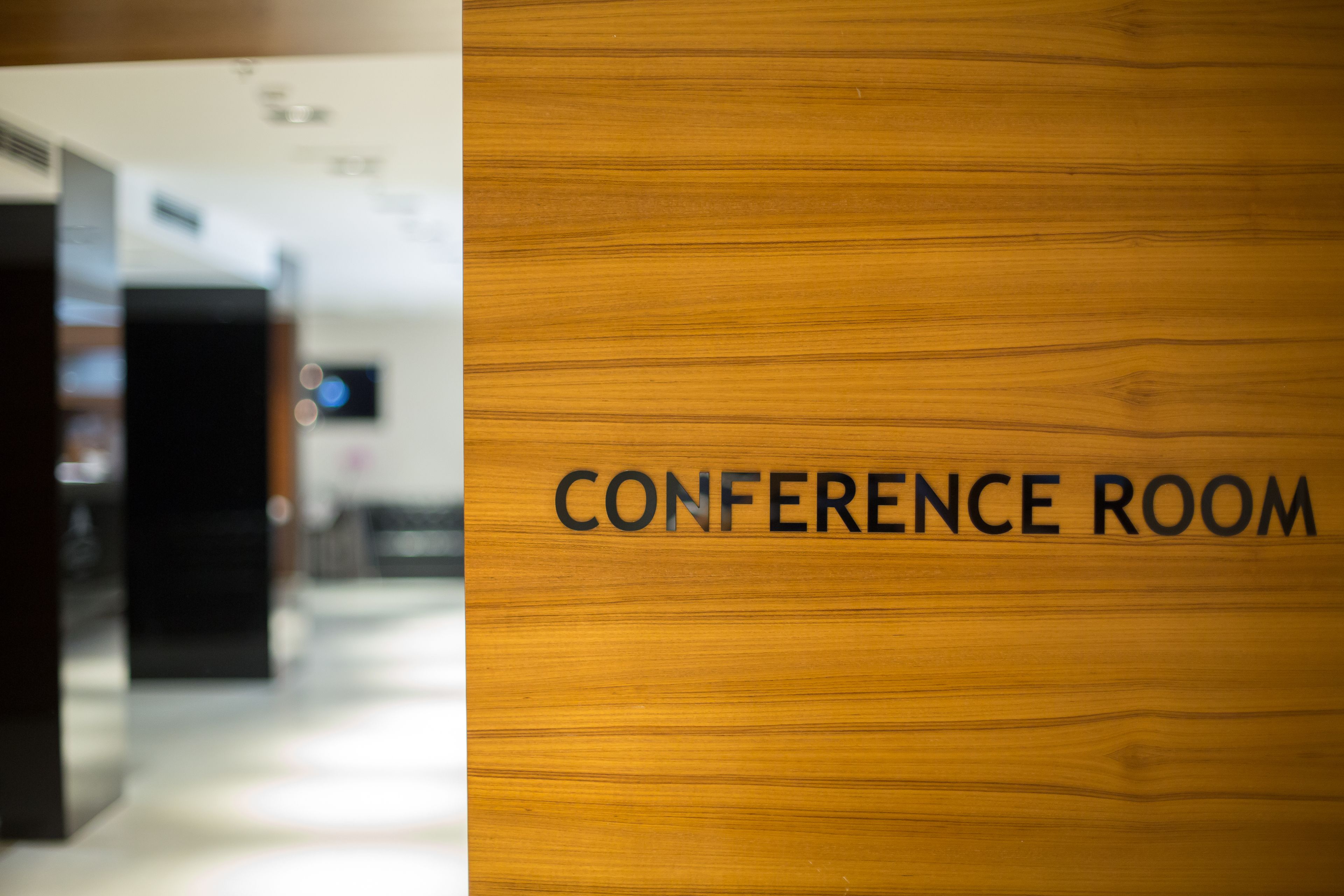 Uma porta de madeira com a inscrição "CONFERENCE ROOM", indicando um espaço reservado para reuniões ou eventos.