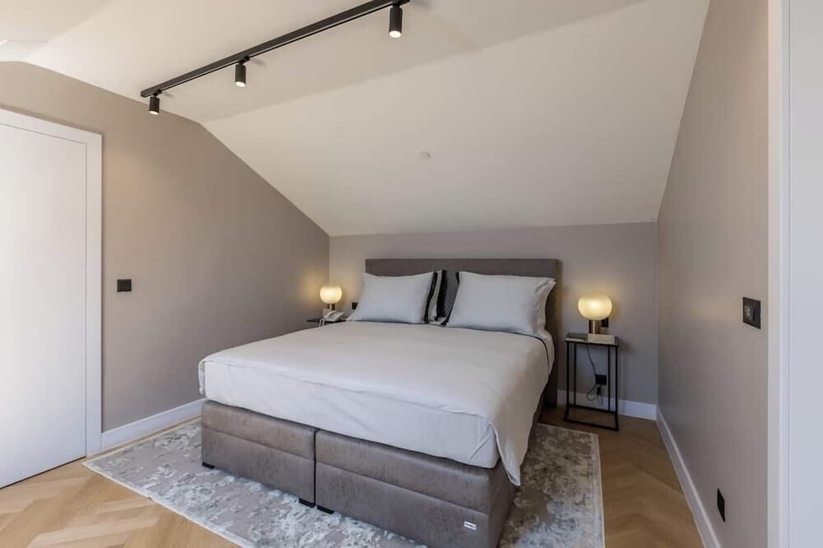 A bedroom with a bed, bedside lamps, a nightstand, and a ceiling light fixture.