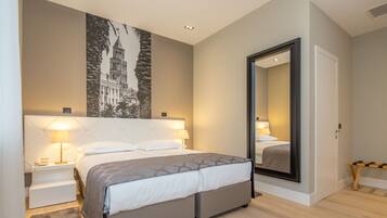 Un hotel moderno con una cama grande, lámparas de noche, un espejo y un cuadro en la pared.