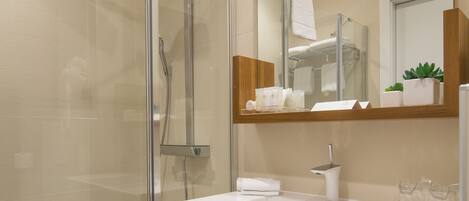 A modern bathroom with a glass-enclosed shower, a white sink, and a large mirror.