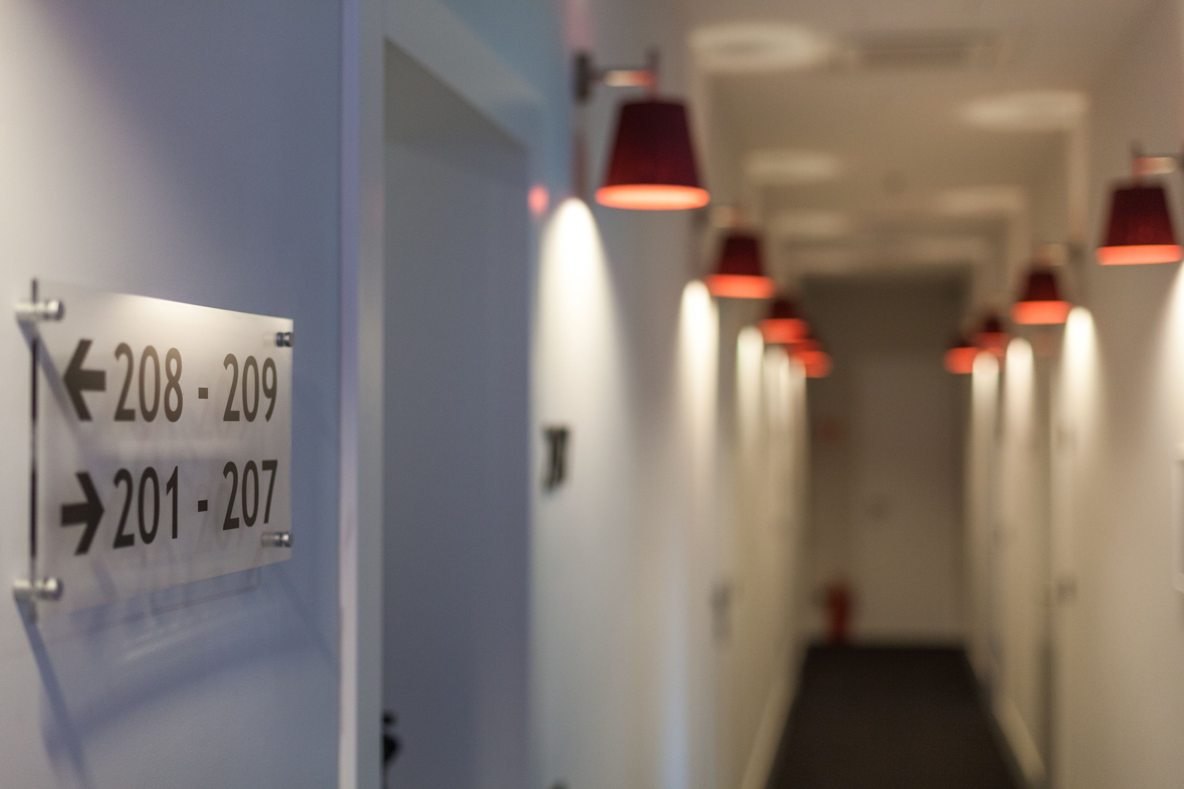 Un couloir avec des panneaux indicateurs indiquant les numéros des chambres : 208-209 et 201-207.