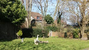 A backyard with a lawn, a bird feeder, and a statue of a bird.