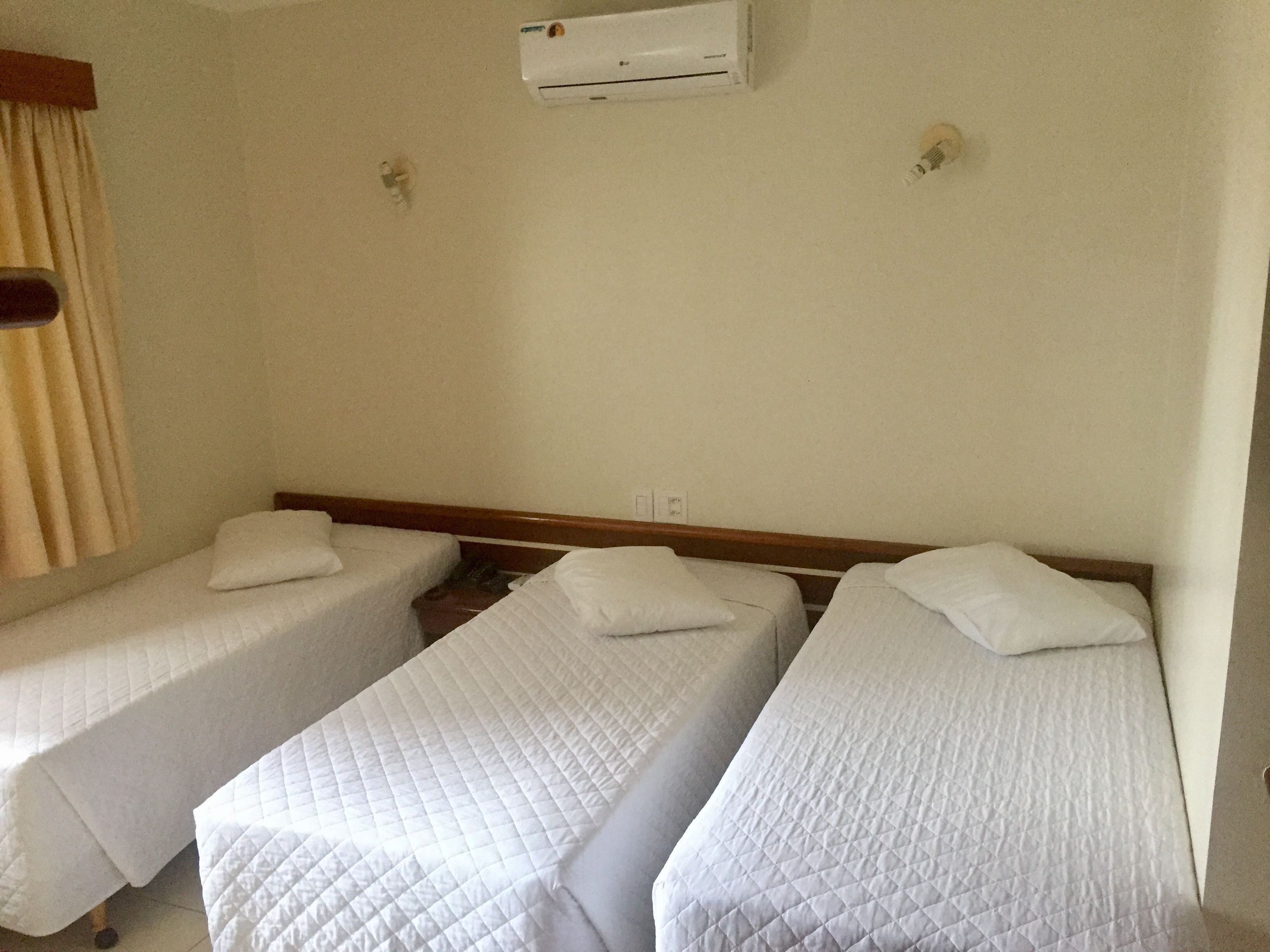 Ein Zimmer mit zwei Einzelbetten, einer Deckenklimaanlage und einer schlichten Wand.