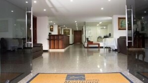 A hotel lobby with a reception desk, seating area, and a dining table.