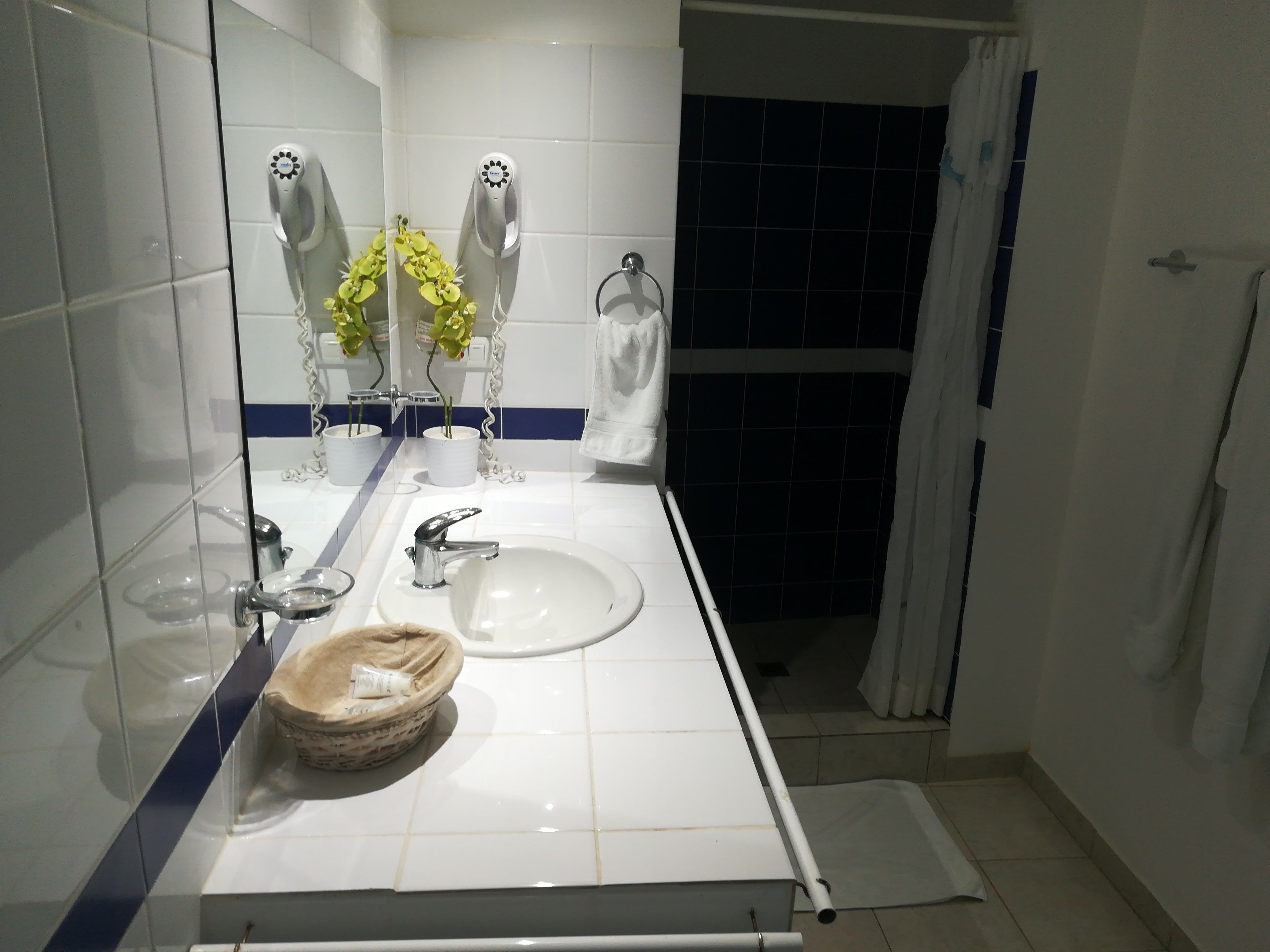 A modern bathroom with a white sink, two hair dryers, and a mirror.