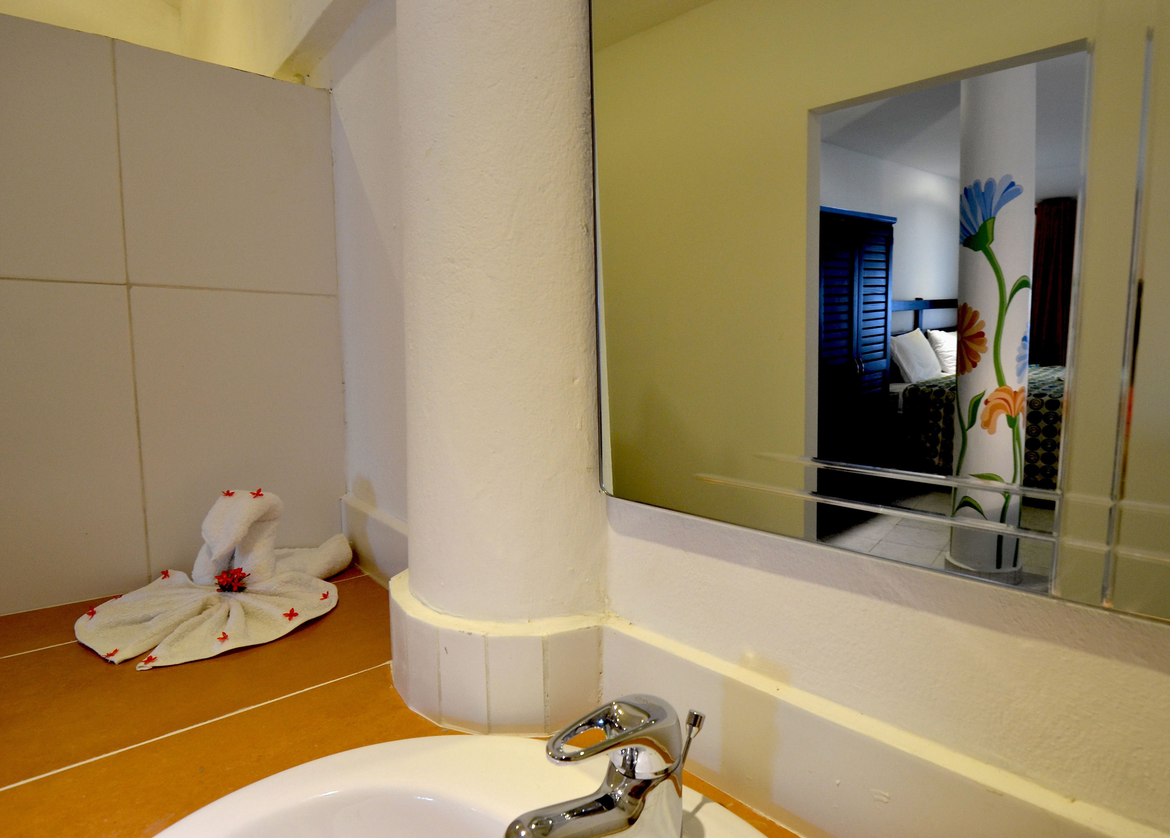 Un baño con un lavamanos blanco, un espejo y una toalla en el suelo.