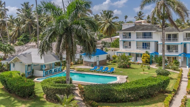 A resort with a pool, palm trees, and a two-story building with balconies. - Costarena Beach Hotel (Las Terrenas)