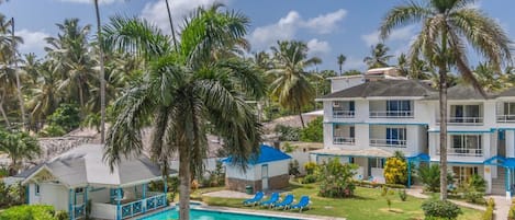 Una piscina al aire libre, sombrillas, sillones reclinables de piscina