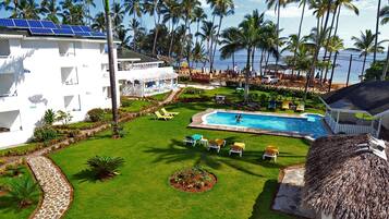 Un resort con piscina, sillas de sol y vista al océano.