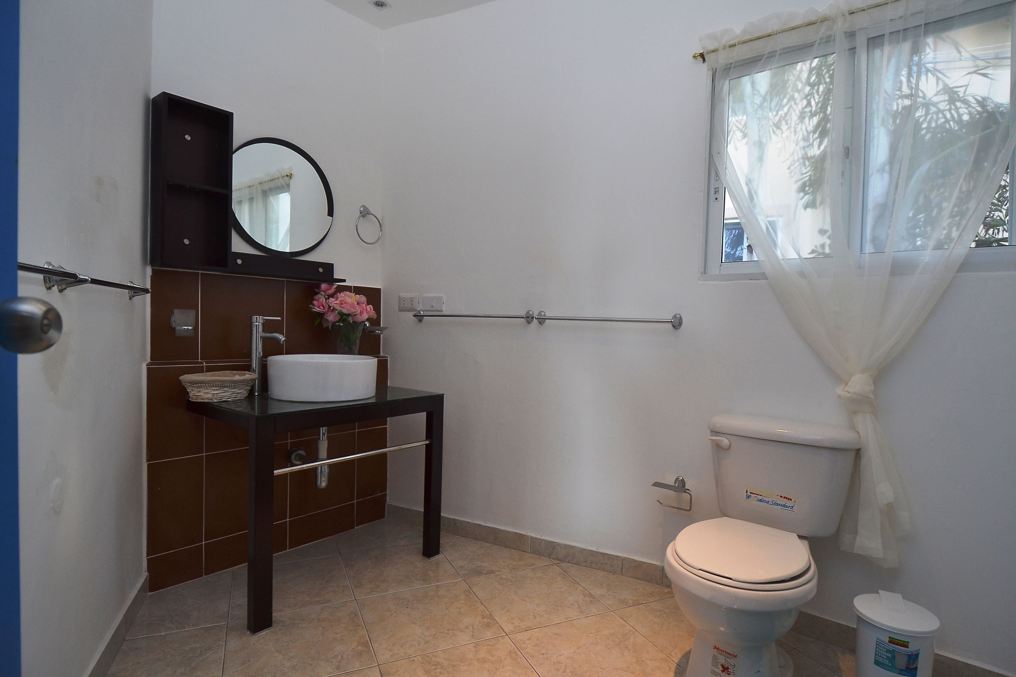 A bathroom with a toilet, sink, and mirror.