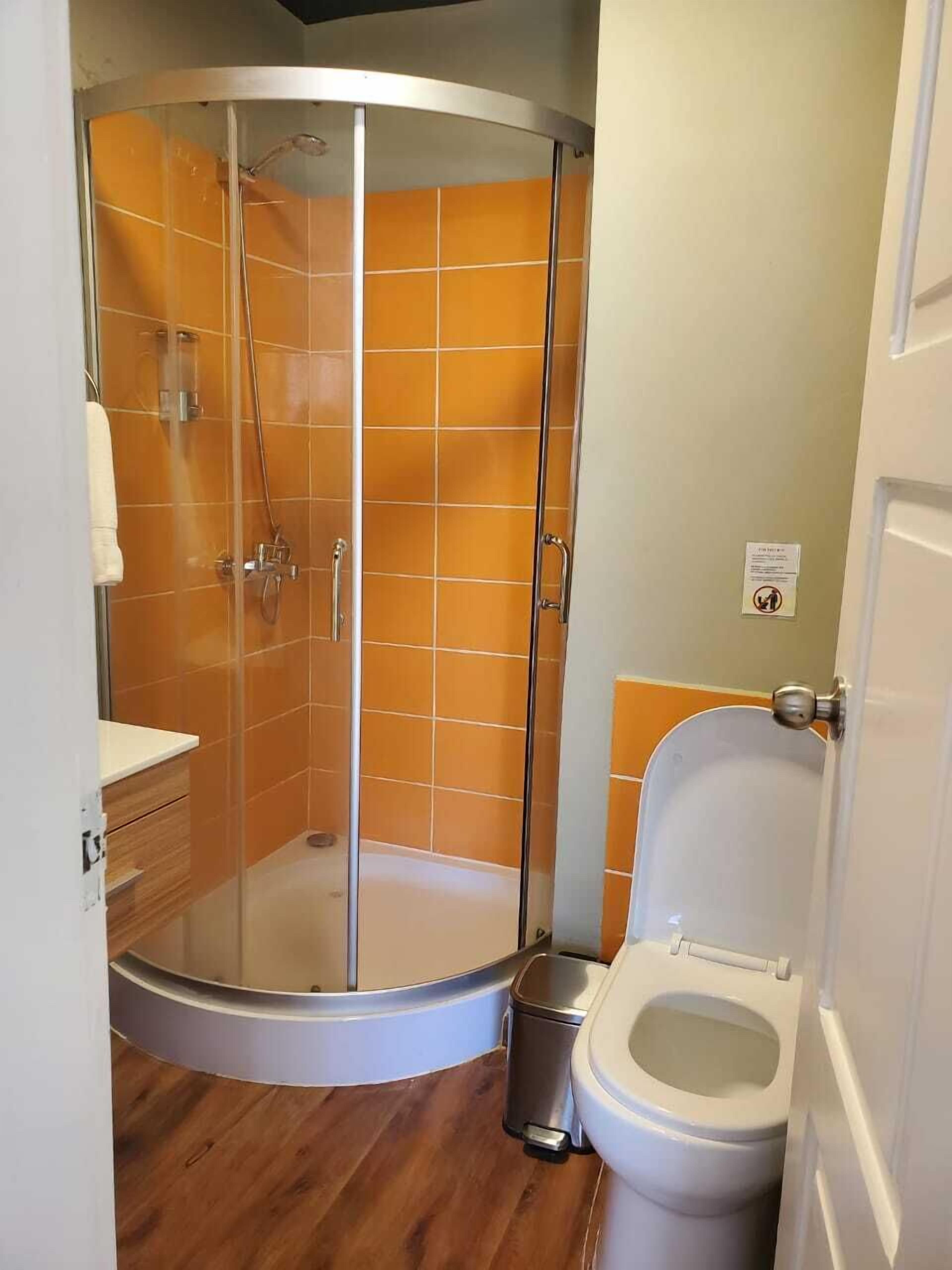 Ein Badezimmer mit einer Duschkabine, einer Toilette und einem Mülleimer.