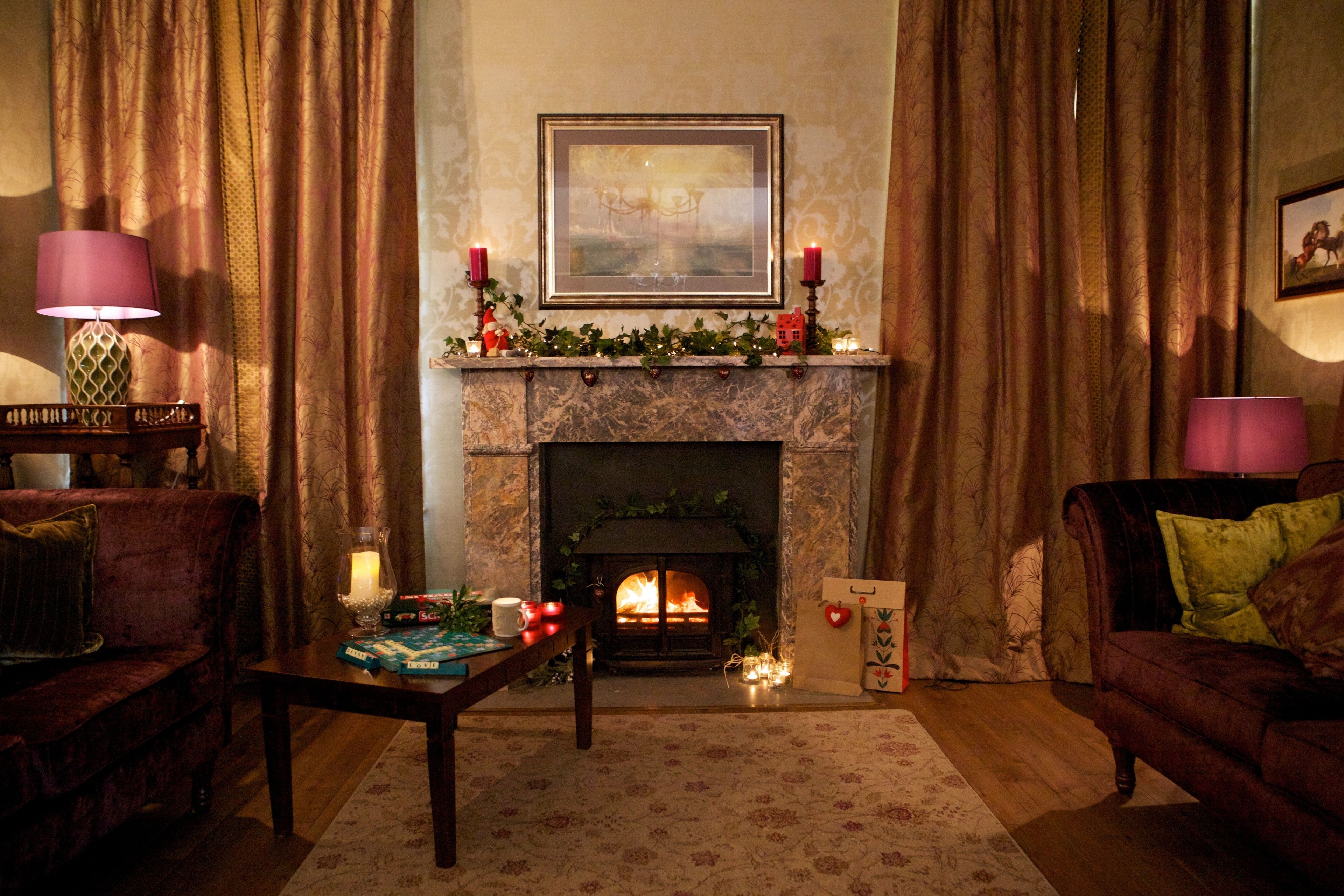 Una sala de estar acogedora con chimenea, un sofá, una mesa y una lámpara.