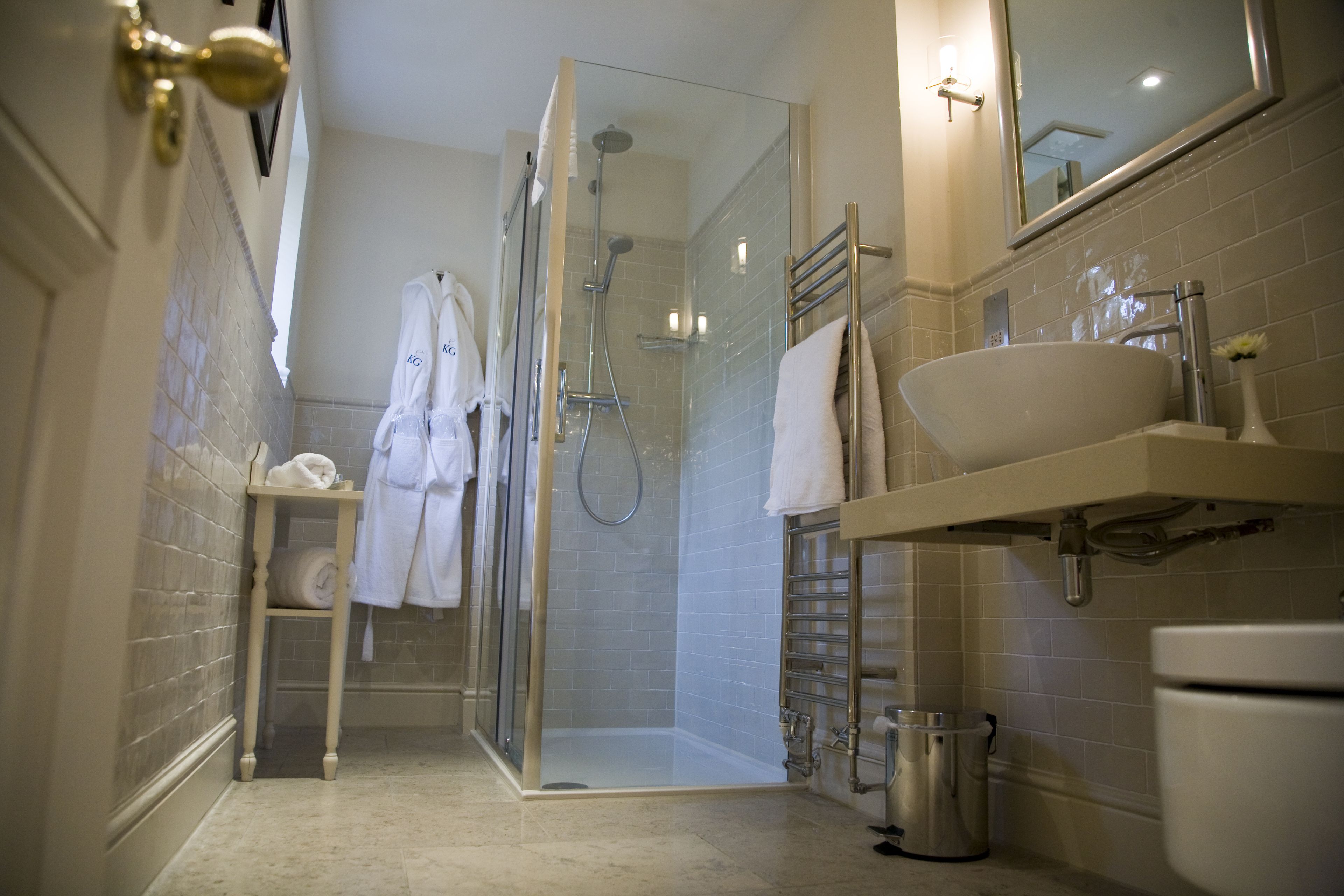 A modern bathroom with a glass-enclosed shower, a sink, and a towel rack.