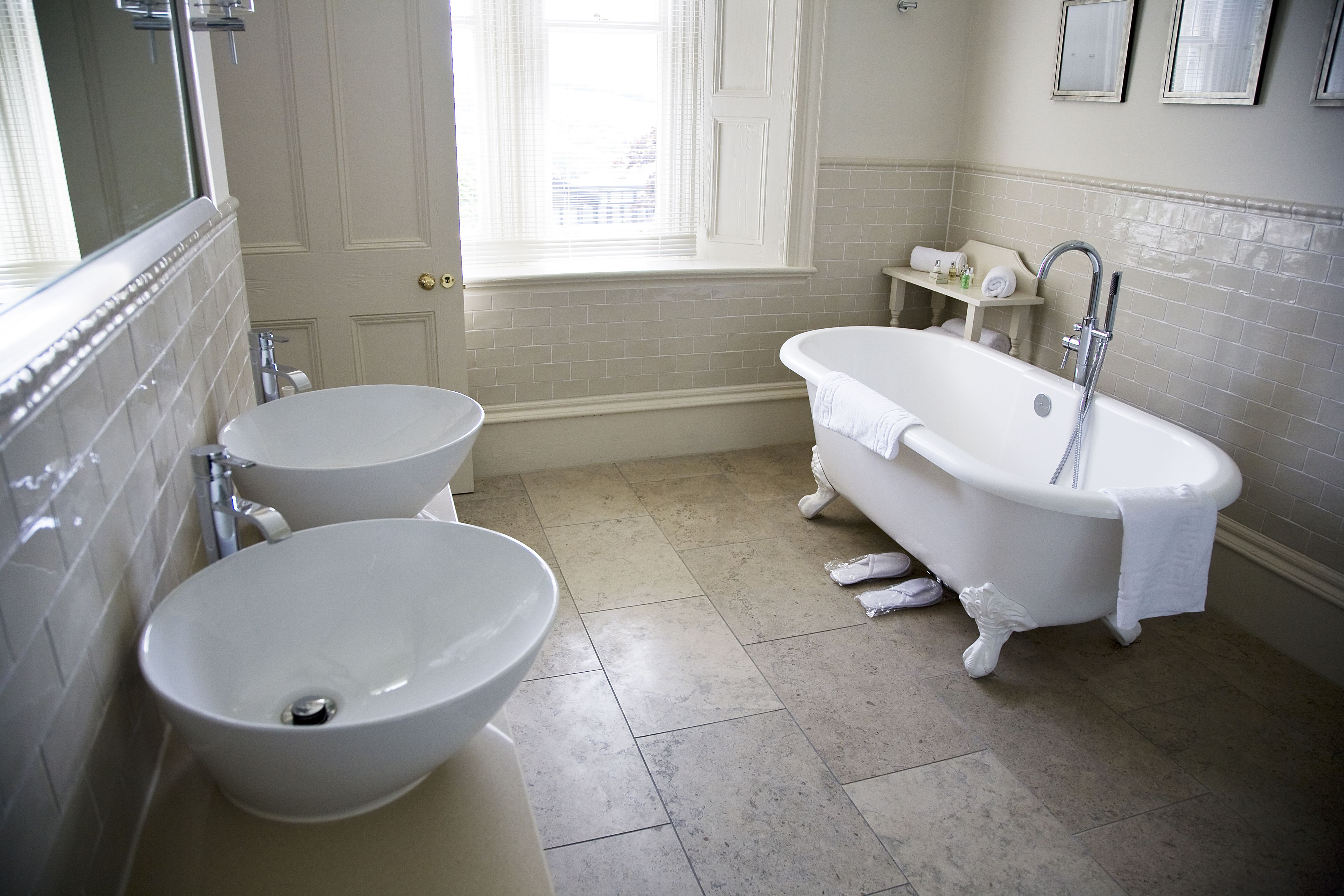 A bathroom with a bathtub, two sinks, and a window.