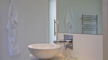 A bathroom with a large white sink, a mirror, and a towel rack.