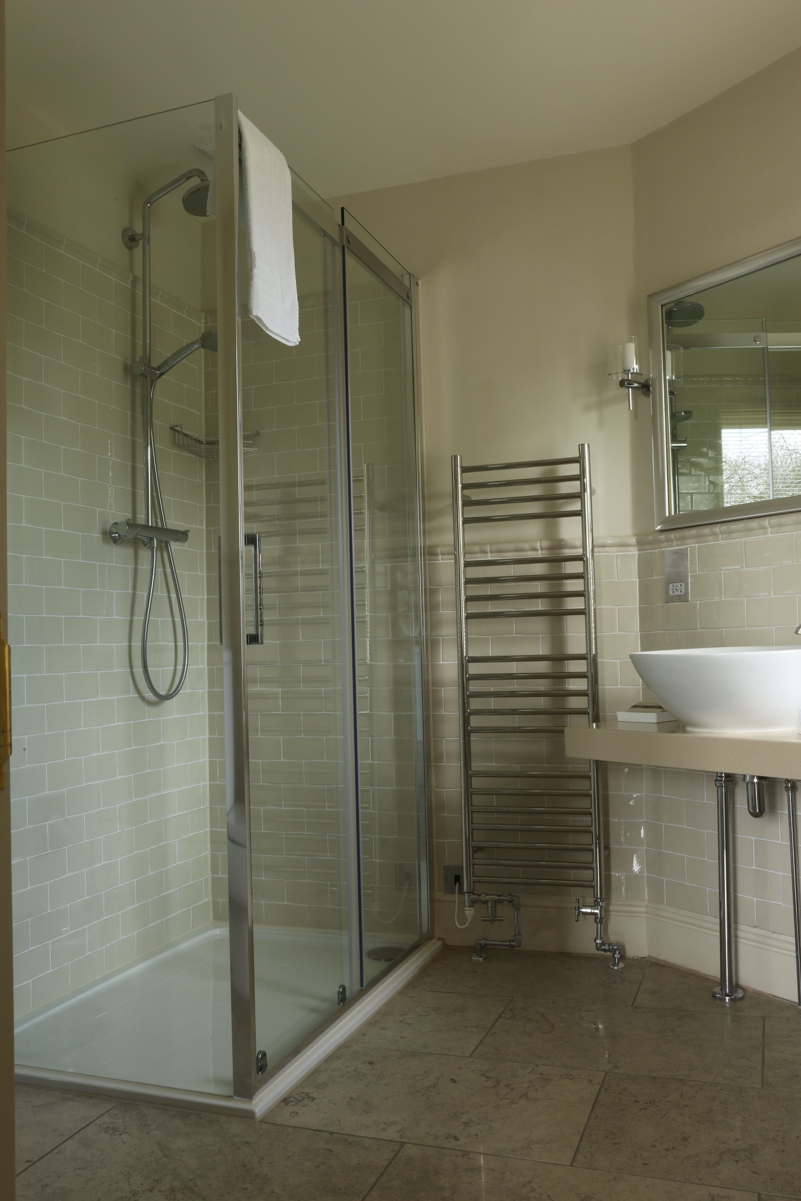 A modern bathroom with a glass-enclosed shower, a white sink, and a towel rack.