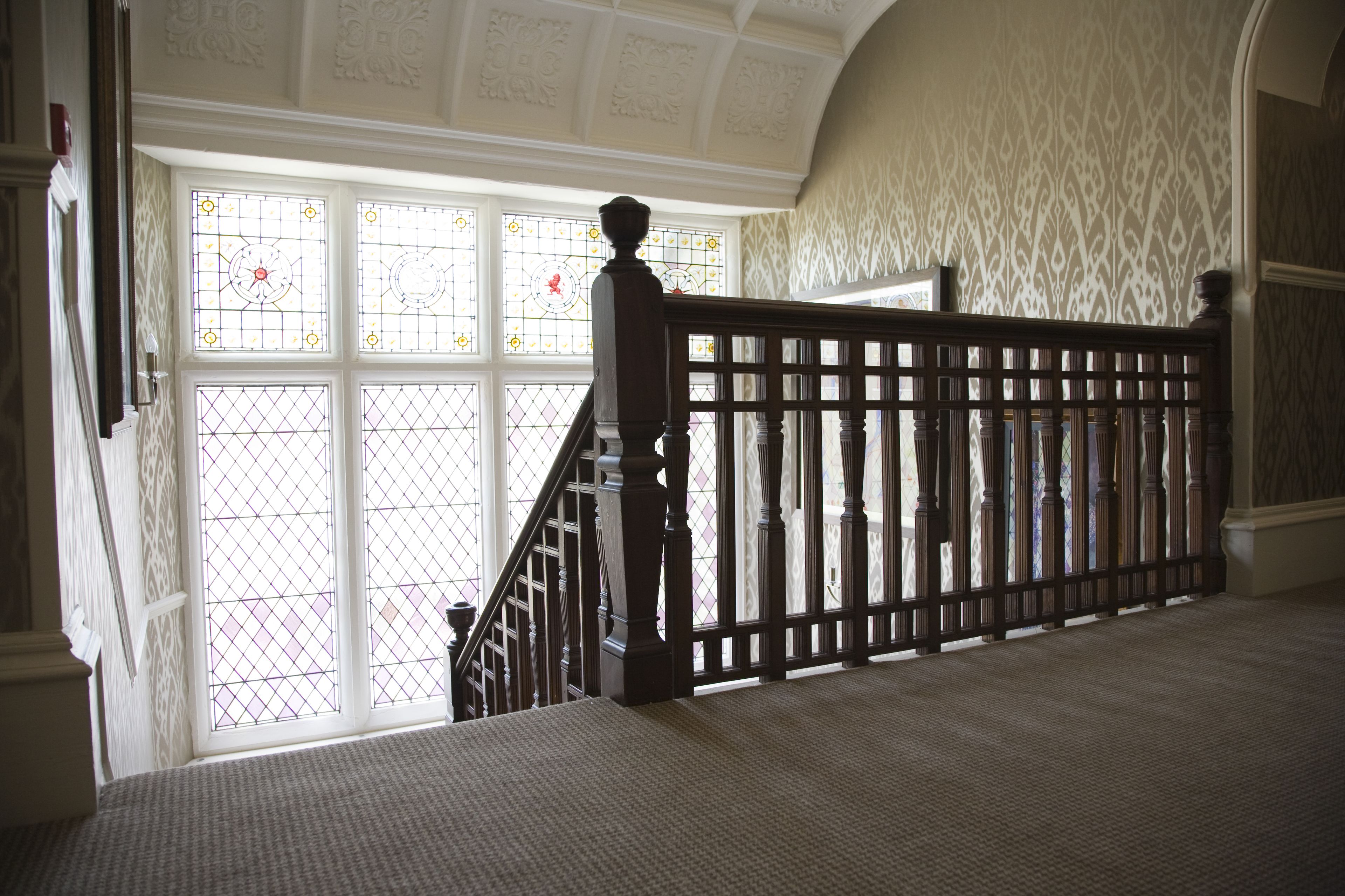 A staircase with a wooden railing leading to a door with stained glass windows.