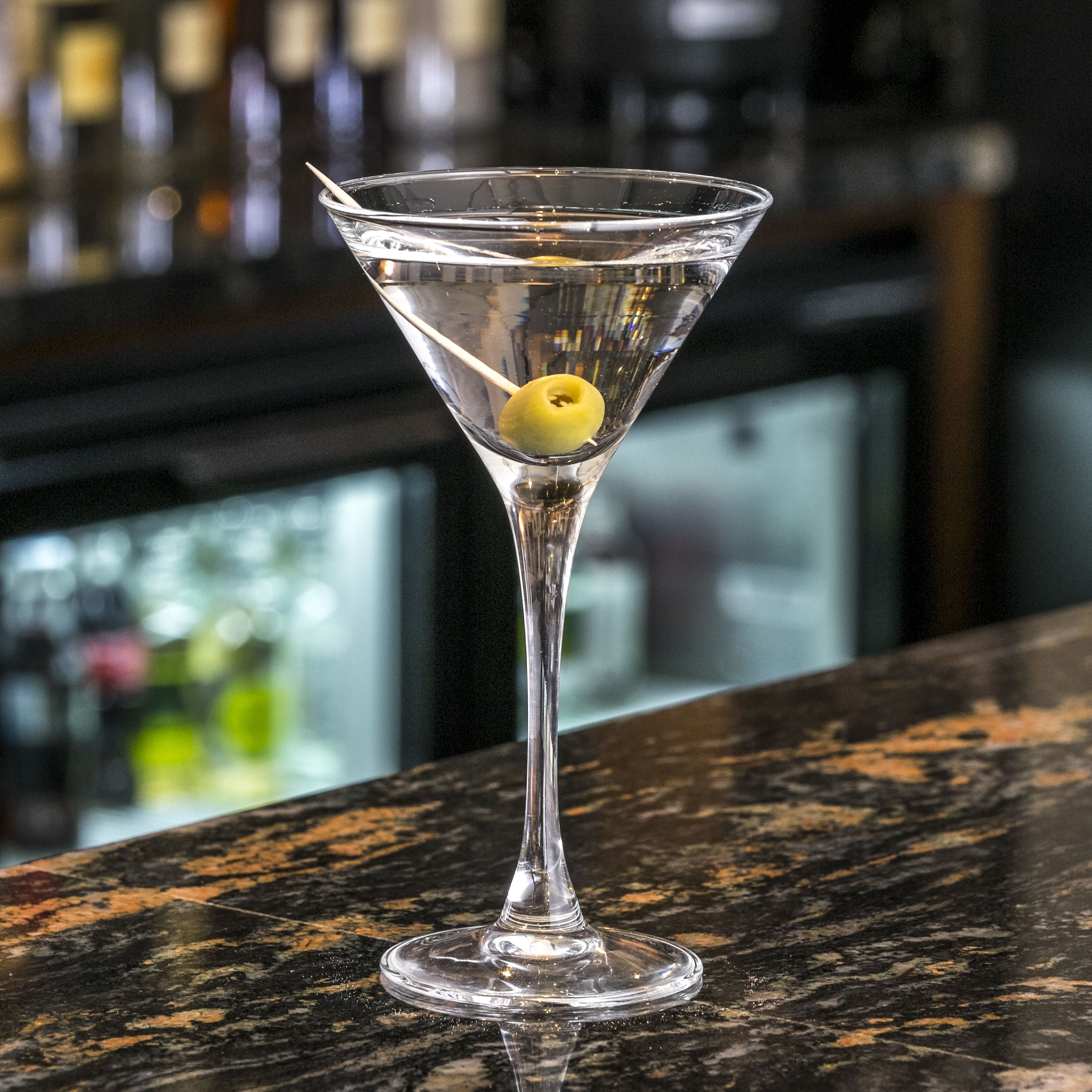 A martini glass with a lemon on a bar counter.