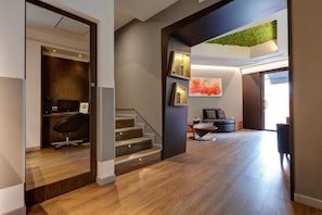 Un interior moderno con una escalera, una zona de estar y una planta verde colgada en la pared.