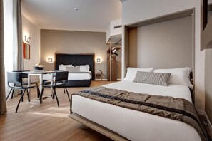Una habitación de hotel moderna con una cama grande, un escritorio con silla y un armario.