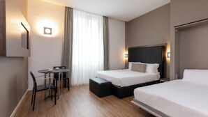 A hotel room with two beds, a desk with chairs, a small table, and a window with curtains. - Rome Art Hotel - Trevi Hotels Group (Rome)