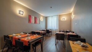 A hotel dining area with tables set for meals, chairs, and artwork on the walls. - Rome Art Hotel - Trevi Hotels Group (Rome)