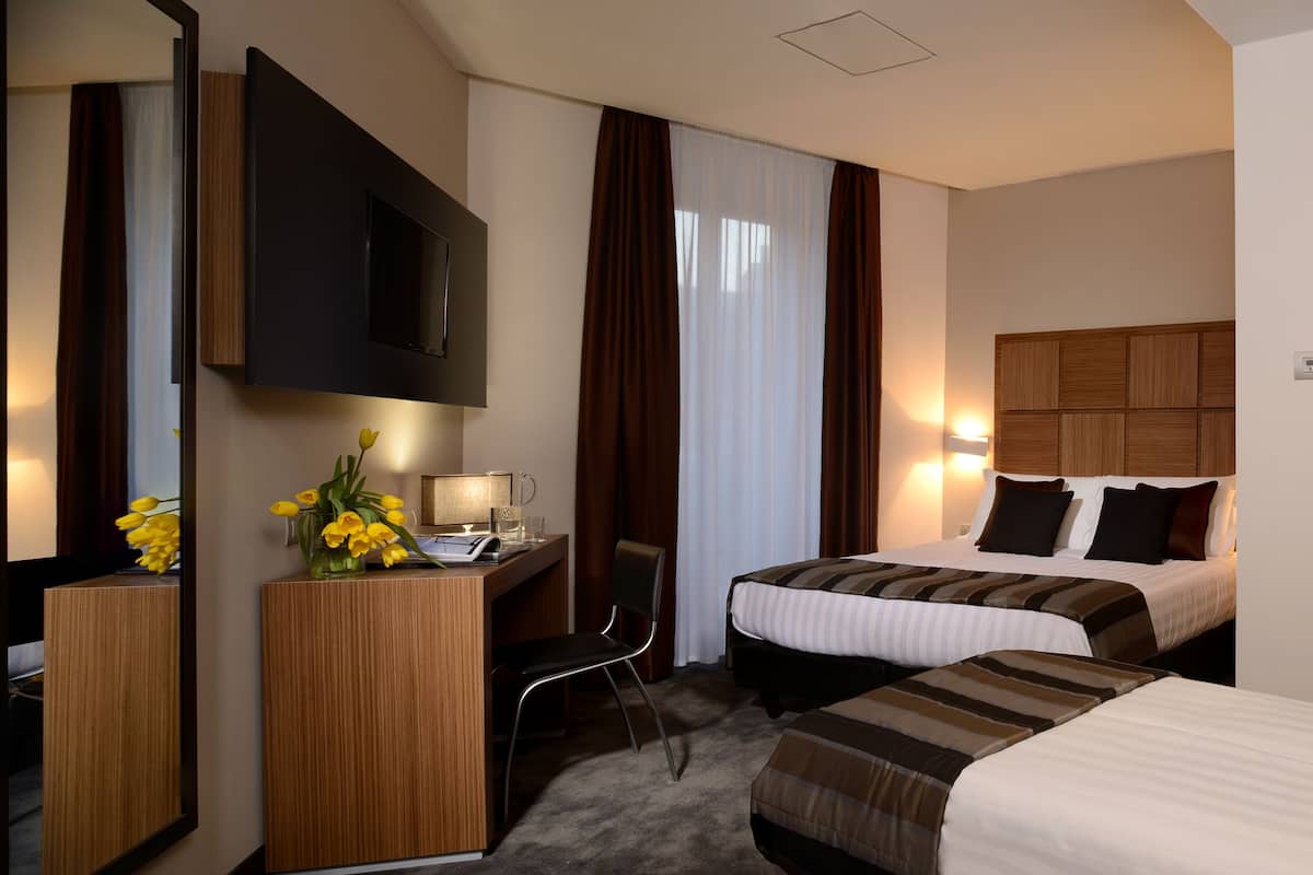 Une chambre d’hôtel avec deux lits, un bureau, une chaise, une télévision et une porte.