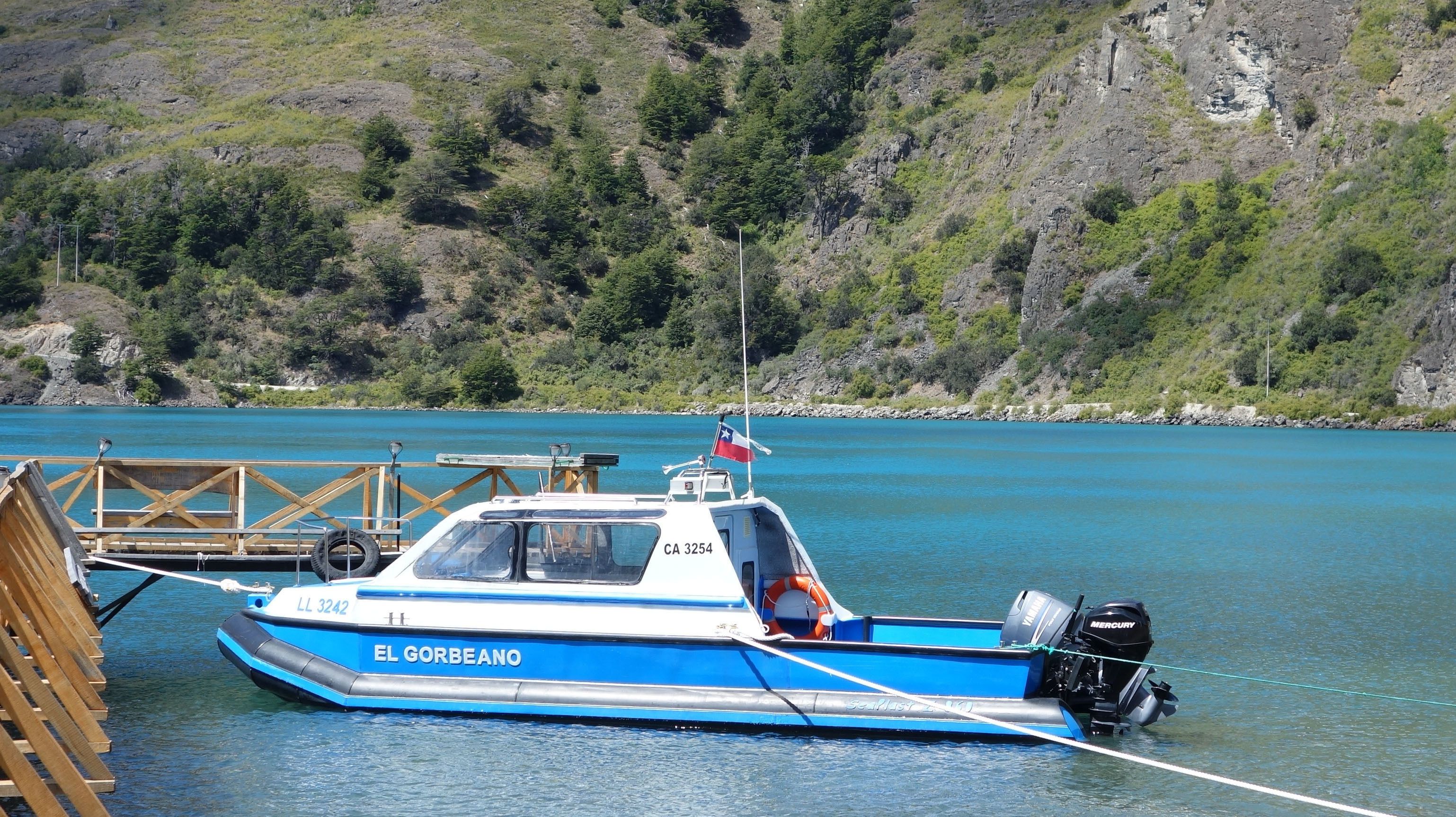 A blue boat named EL GORBEANO docked at a wooden pier.