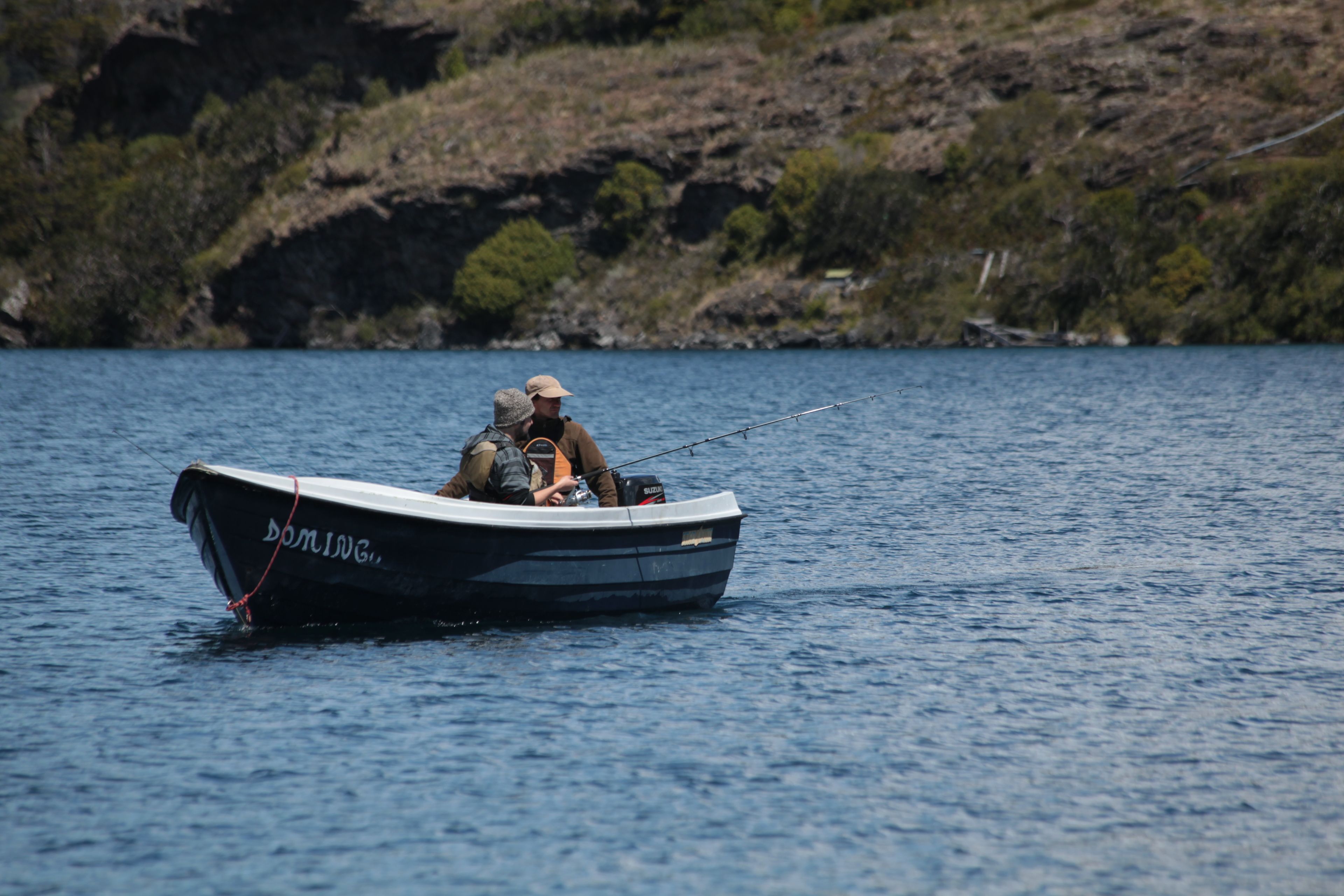 Ein kleines Boot mit dem Namen 'DOMINGO' auf ruhigem Wasser.