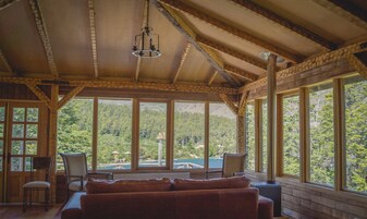 A cozy cabin interior with a large window offering a scenic view of a forested area.
