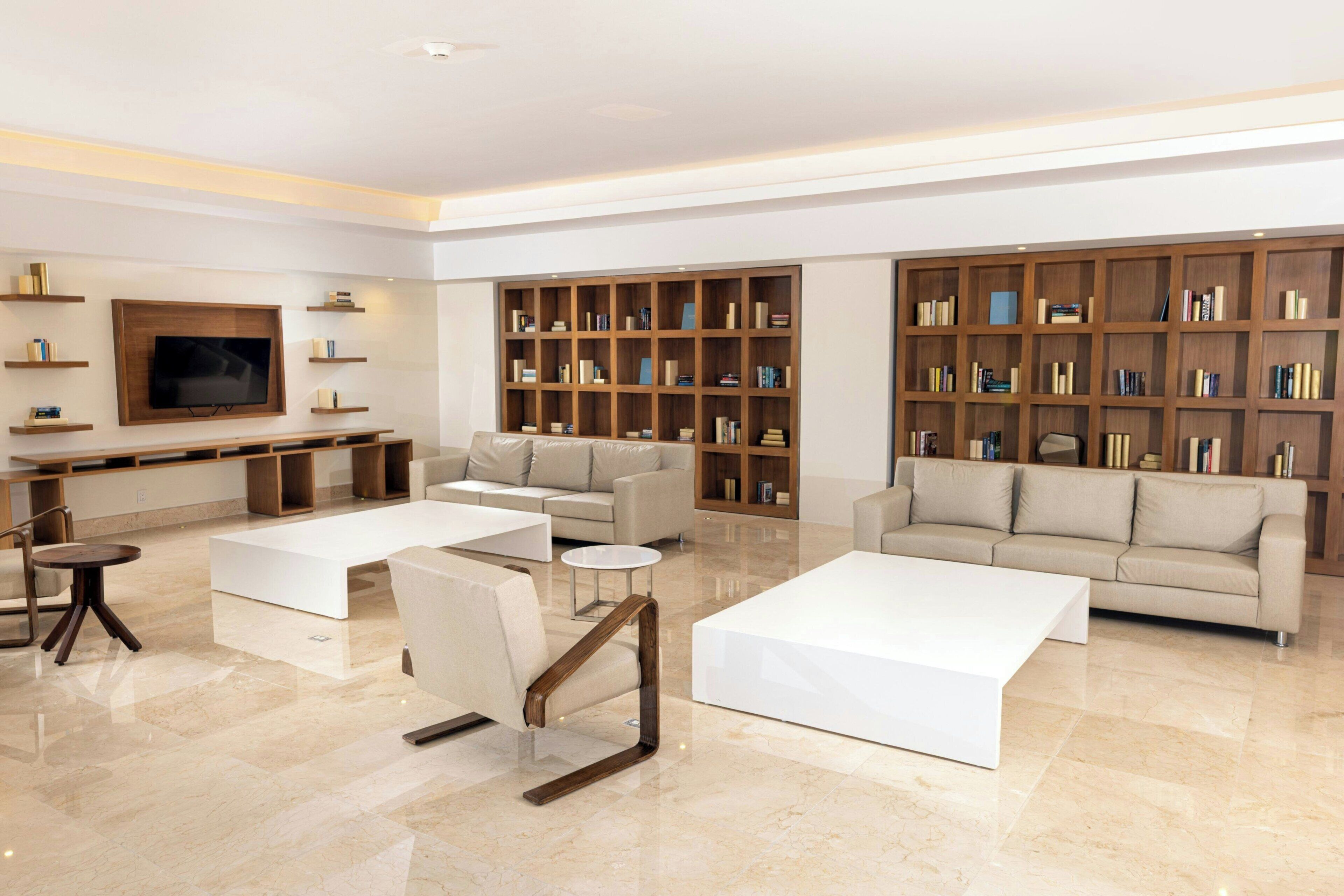 A modern living room with a flat-screen TV, two sofas, a coffee table, and a bookshelf.