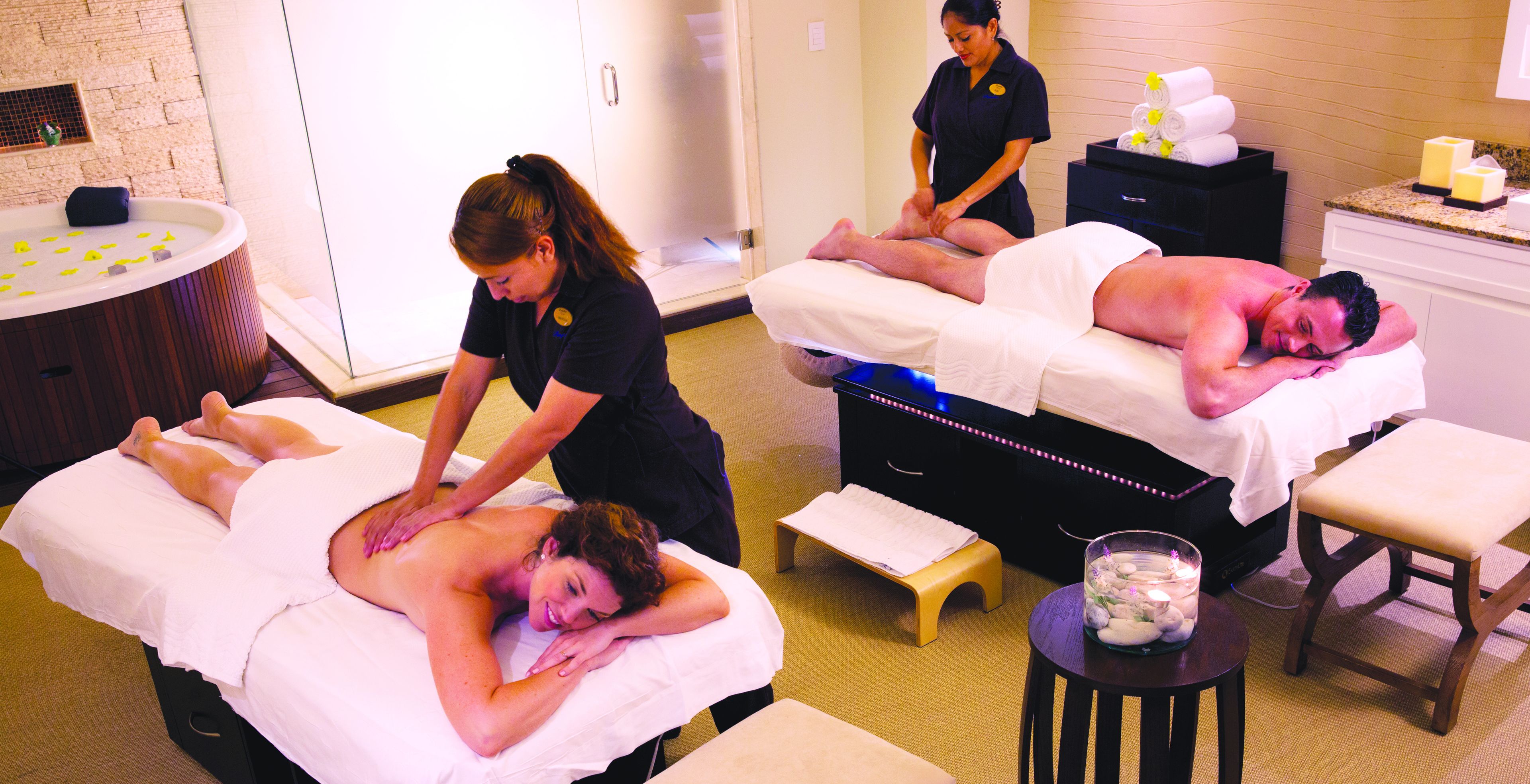 A massage therapy room with two massage tables, a small stool, and a table with candles.