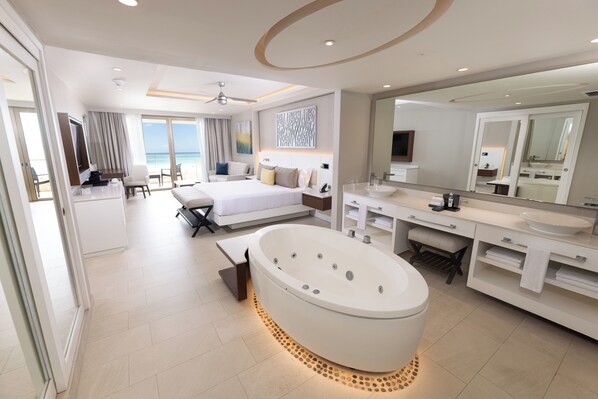 Una habitación de hotel moderna con una cama grande, una bañera, un tocador con espejo y vista a la playa.