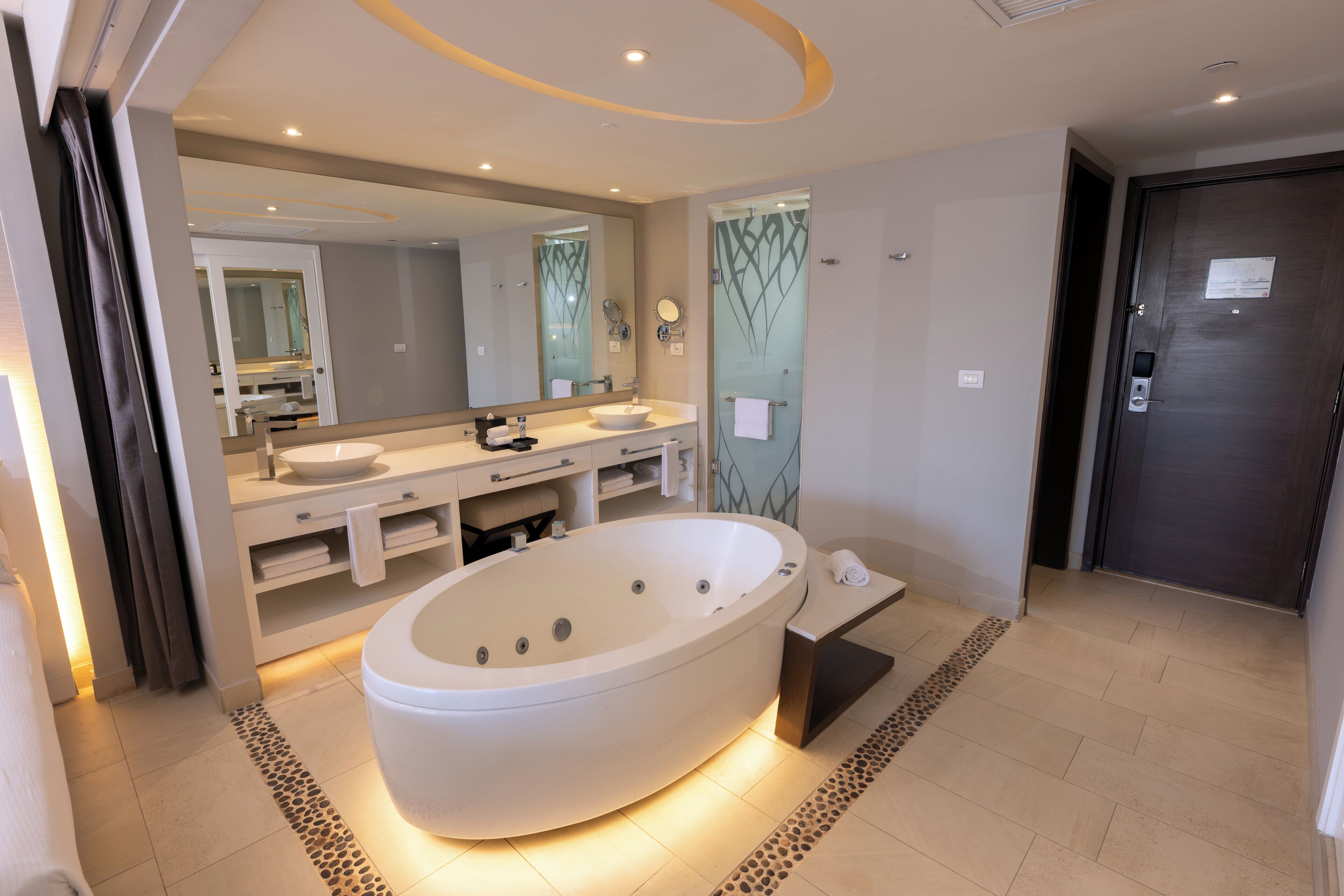 A modern bathroom with a freestanding bathtub, dual sinks, and a large mirror.