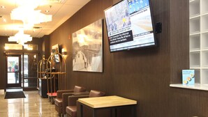 A lobby with a TV displaying news, seating areas, and a reception desk. - The Saint James Hotel, an Ascend Collection Hotel (Toronto)