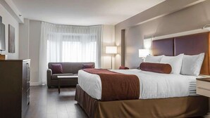 A hotel room with a large bed, a sofa, a desk, and a wardrobe. - The Saint James Hotel, an Ascend Collection Hotel (Toronto)
