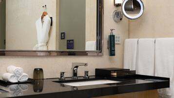 A bathroom with a large mirror, a sink, a towel rack, and a bottle of body lotion.