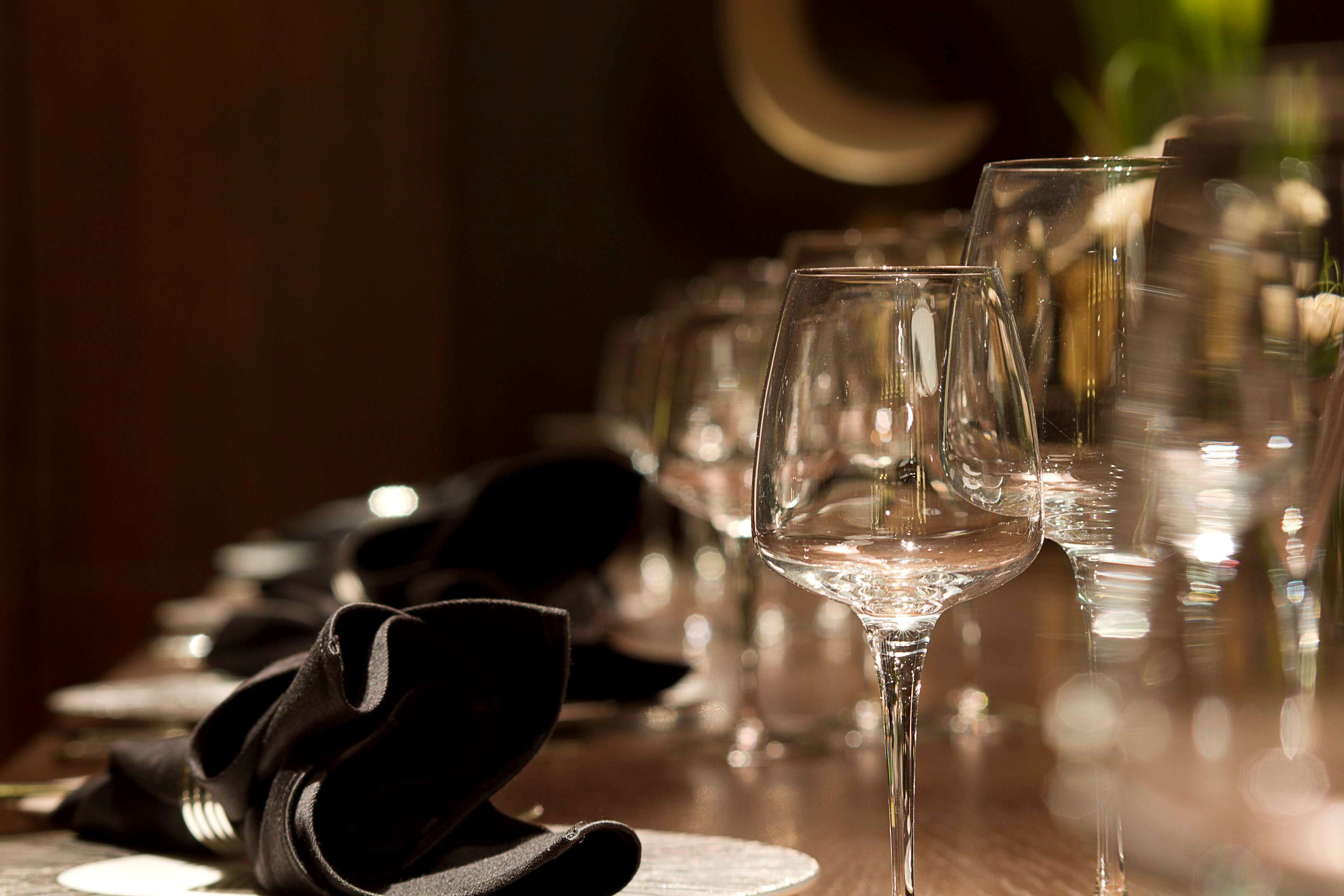 A table set with wine glasses and black napkins, indicating a formal dining setup.