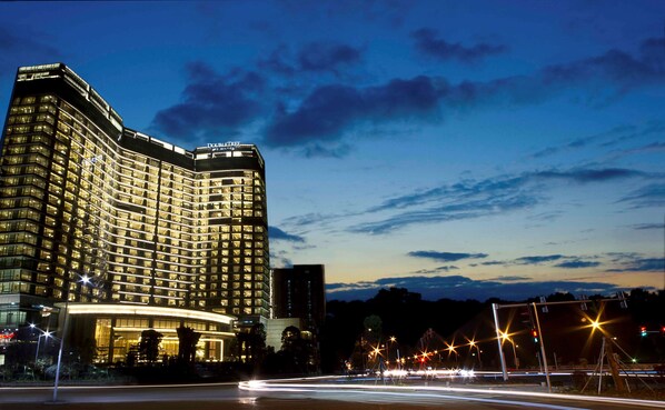 A high-rise hotel with a curved facade, multiple floors, and illuminated windows.