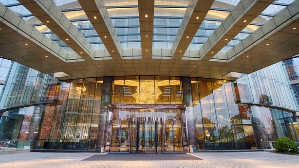 A modern building with a glass facade and a central revolving door entrance. - DoubleTree by Hilton Hotel Heyuan (Heyuan)