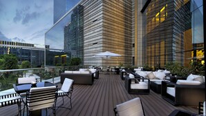 A rooftop terrace with outdoor seating, a glass balustrade, and a view of a cityscape. - DoubleTree by Hilton Hotel Heyuan (Heyuan)