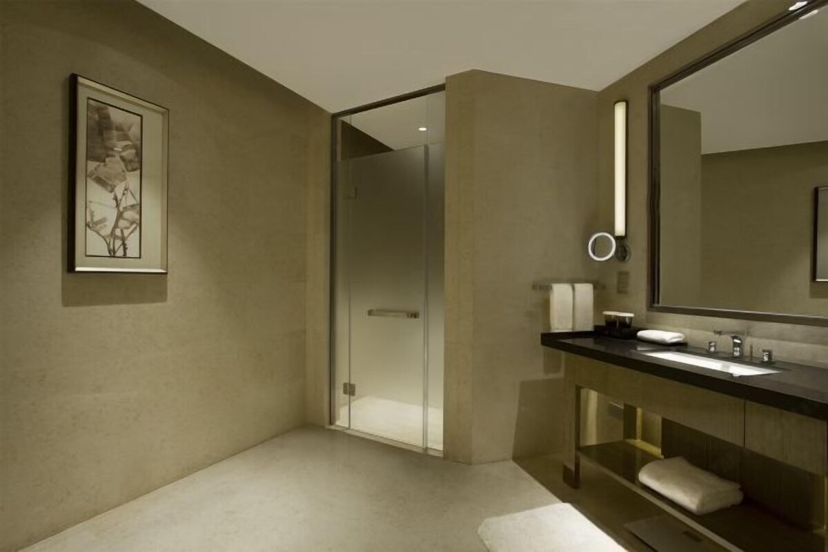 Un baño moderno con un espejo grande, un lavamanos y una cabina de ducha de vidrio.