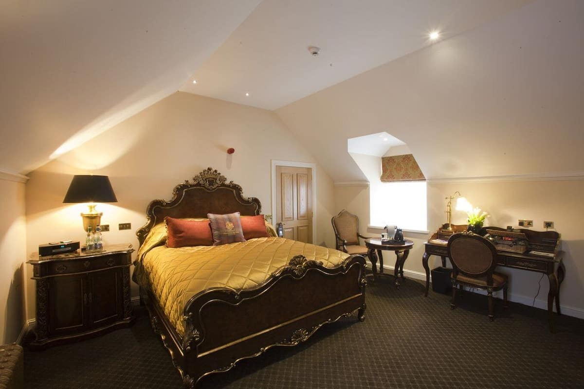 A bedroom with a large bed, a desk, a chair, and a small table.