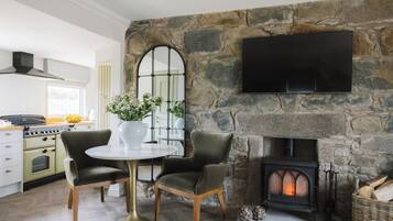 Una cocina moderna con pared de piedra, chimenea y televisor de pantalla plana montado encima.