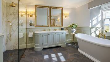 A bathroom with a marble shower, a freestanding bathtub, and a vanity with a double mirror.