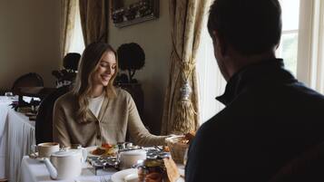 A dining table with plates of food, a teapot, and a candle.